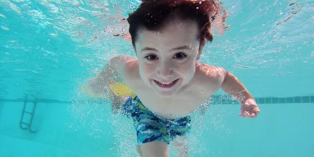 enfant nageant sous l'eau en piscine